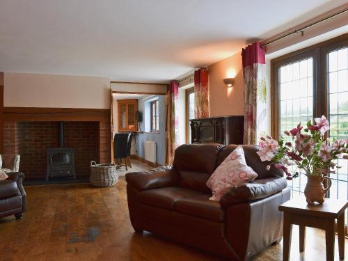 a living room with a leather couch and a fireplace at Celyn in Montgomery