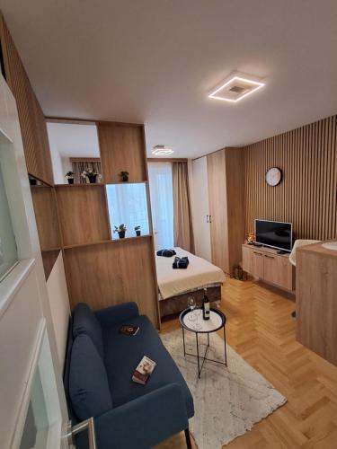 a living room with a bed and a blue couch at Apartman Pahuljica in Pale