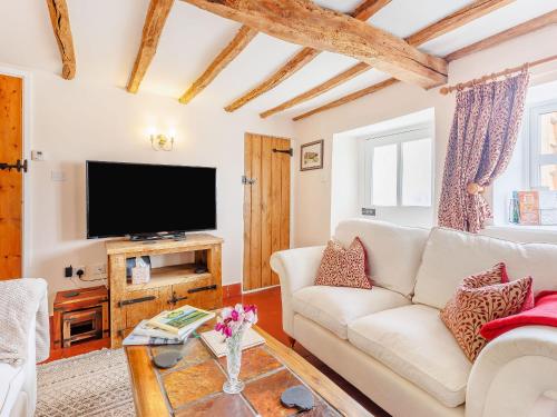 een woonkamer met een witte bank en een tv bij Elsie's Cottage in Pontesbury