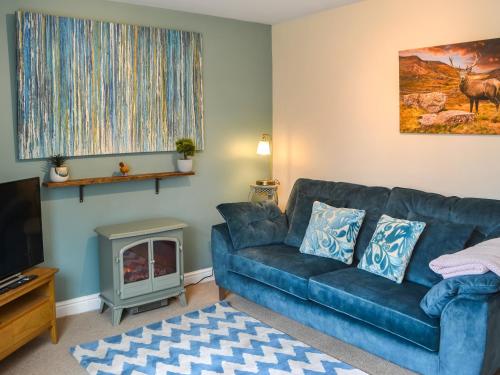 a living room with a blue couch and a fireplace at Grooms Cottage in Choppington