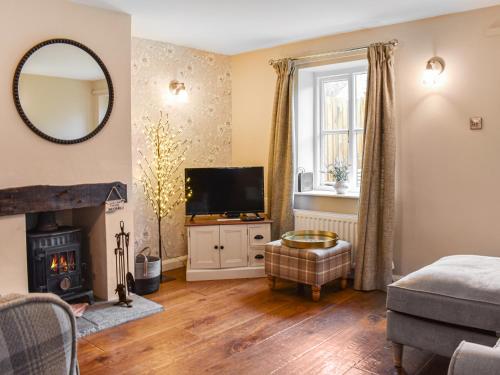 a living room with a television and a fireplace at Uk45895 - Cross House Cottage in Kirkby Lonsdale