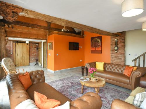 Una sala de estar con muebles de cuero y paredes naranjas. en Orchard Barn - Uk47458, en Chetton