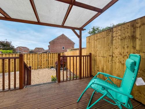 einem blauen Stuhl auf einer Terrasse mit einem Zaun in der Unterkunft Cayton Cove Cottage in Cayton