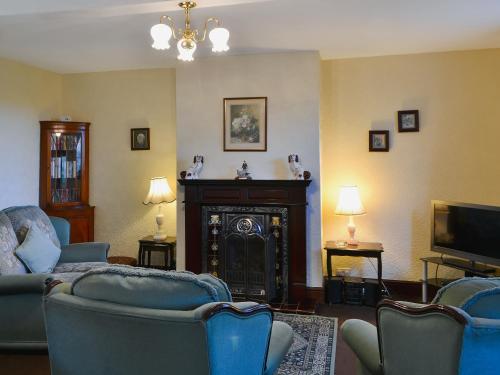 sala de estar con sillas azules y chimenea en The Coach House, en Wetheral