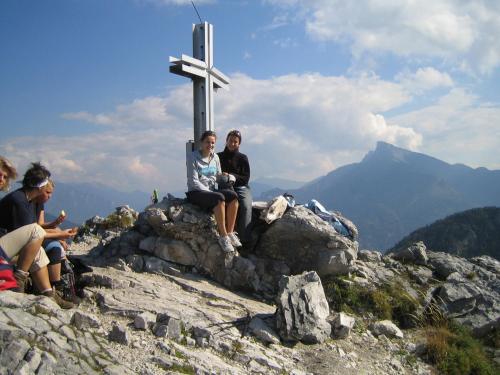 three people sitting on top of a cross on a mountain at Ferienwohnung Winklhofer in Mondsee