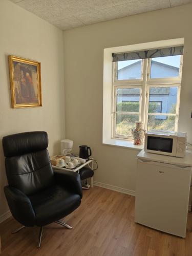 a living room with a chair and a microwave at House on Vellingtoft in Kværs - apartment and deluxe rooms in Gråsten