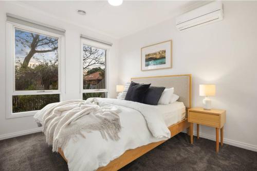 Un dormitorio blanco con una cama y dos ventanas. en Tranquil Highett House With Storage-2k From Beach!, en Highett