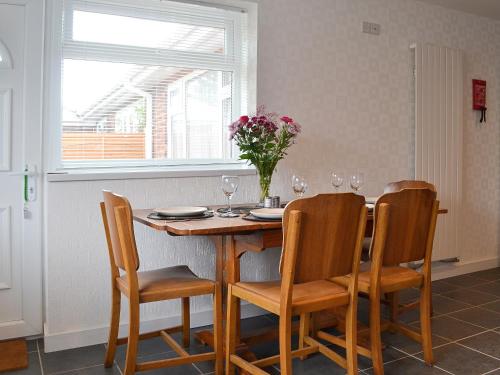 ein Esstisch mit Stühlen und einer Vase mit Blumen in der Unterkunft The Briar Rose in New Herrington