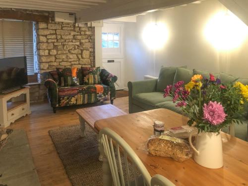 ein Wohnzimmer mit einem Tisch mit Blumen darauf in der Unterkunft The Street Cottage in Uley