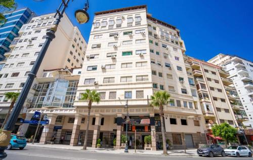 a tall white building on a city street with palm trees at Tradicional & Luxury Apartment City Center & Beach & WiFi! in Tangier
