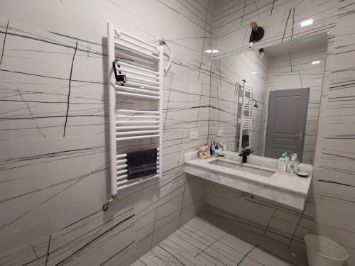 Un baño blanco con lavabo y espejo. en Au cœur de Demina, en Demina