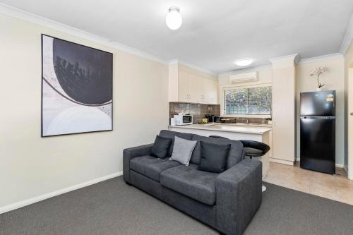 Una sala de estar con un sofá y una cocina. en Wagga CBD Apartments, en Wagga Wagga