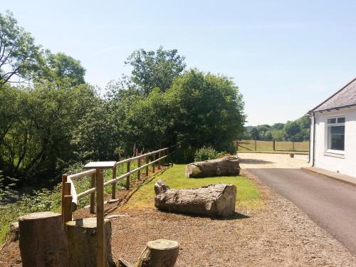 einen Zaun und Holzscheite an der Straßenseite in der Unterkunft Riverside Cottage in Boreland