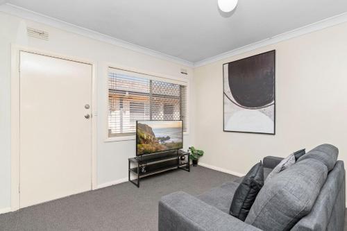 Una sala de estar con un sofá y un televisor de pantalla plana. en Wagga CBD Apartments, en Wagga Wagga