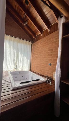 a large white tub in a room with a window at Chales Estância Verdejante in Sapucaí-Mirim