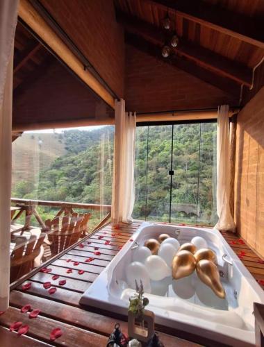 une baignoire dans une pièce avec une grande fenêtre dans l'établissement Chales Estância Verdejante, à Sapucaí-Mirim