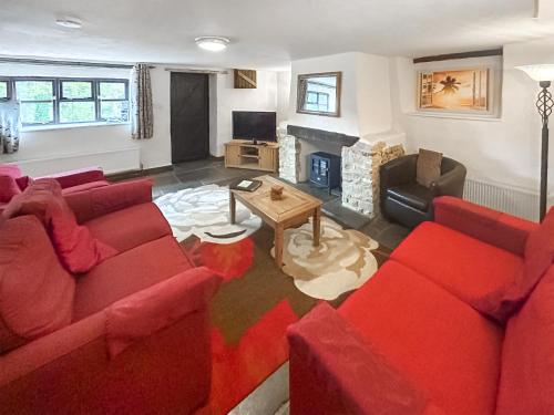 a living room with red furniture and a fireplace at Cider Cottage in Hawkchurch