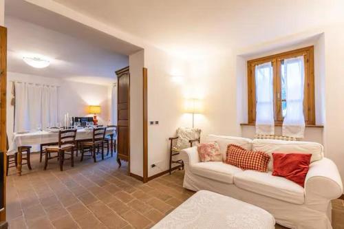 ein Wohnzimmer mit einem weißen Sofa und einem Esszimmer in der Unterkunft Casale il Gugnolo in Castiglione dʼOrcia