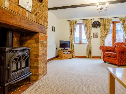 a living room with a brick fireplace and a tv at Pantiles Barn - E3866 in Runcton Holme
