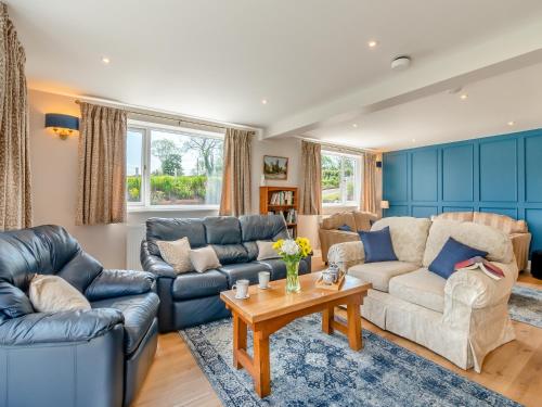 Una sala de estar con sofás y una mesa. en Llwyncelyn Farmhouse, en Clynderwen