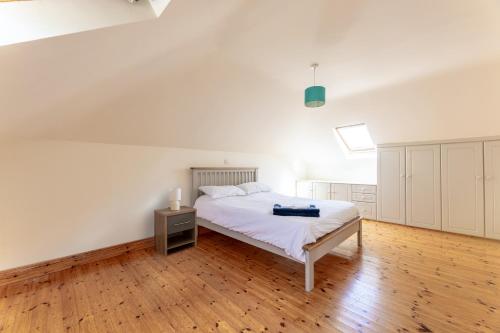 a white bedroom with a bed and a wooden floor at Ballyneill Farmhouse in Carrick-on-Suir