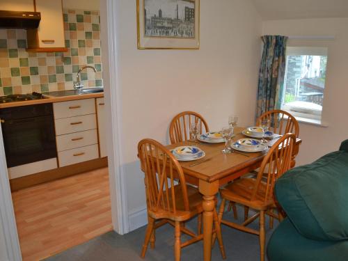 a dining room table with four chairs and a kitchen at Oaklands in Ambleside