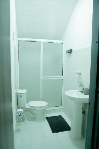 a white bathroom with a toilet and a sink at CASA ROOSEVELT in Cali