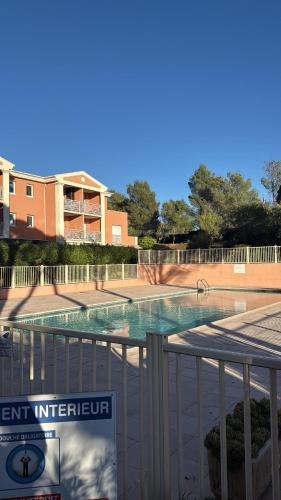 a swimming pool with a sign next to a fence at Charmant T2 refait à neuf, St Raphaël, Valescure in Saint-Raphaël