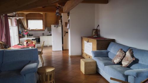 un salon avec un canapé bleu et une cuisine dans l'établissement Lauton Dolomiti Relax Apartment - mit Jacuzzi-Badewanne, à Ziano di Fiemme