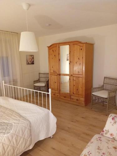 a bedroom with a bed and two chairs and a cabinet at Casa Lobi - Die Ferienwohnung mit Ausblick! in Korbach