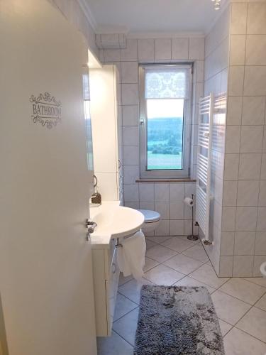 a white bathroom with a sink and a window at Casa Lobi - Die Ferienwohnung mit Ausblick! in Korbach