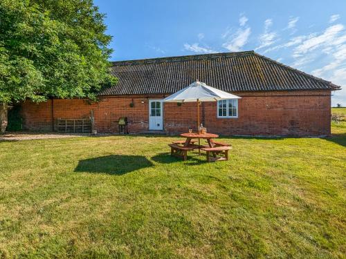 a picnic table with an umbrella in front of a building at The Cottage At Canefield Farmhouse in Mottisfont