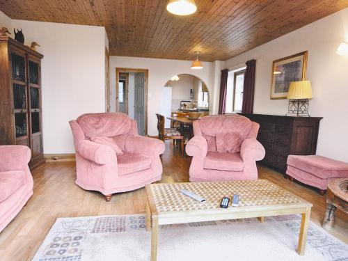ein Wohnzimmer mit rosa Stühlen und einem Couchtisch in der Unterkunft Coast View Cottage - Hw7745 in Pendine