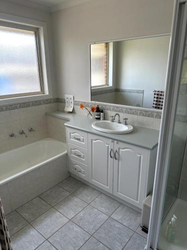 a bathroom with a sink and a tub and a mirror at Beach Escape Torquay in Torquay