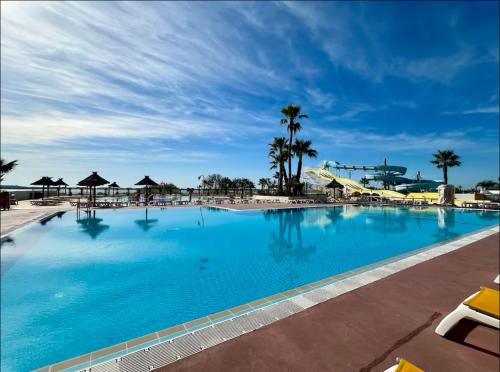 a large blue swimming pool with a roller coaster at Bungalow 507 3ch wifi Camping Siblu Lac de Rêves in Lattes