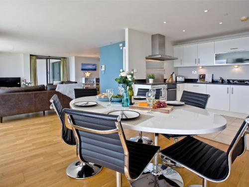 een keuken en woonkamer met een witte tafel en stoelen bij The Penthouse Bay View in Westward Ho