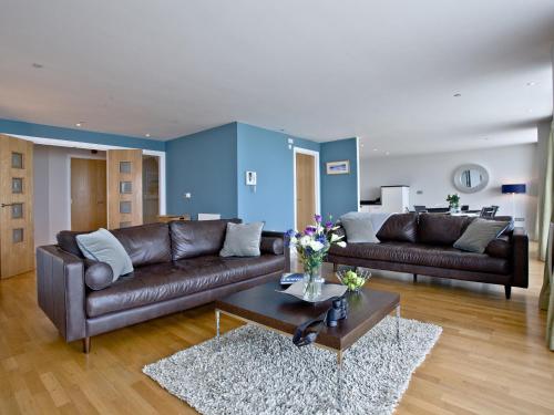 een woonkamer met twee leren banken en een tafel bij The Penthouse Bay View in Westward Ho