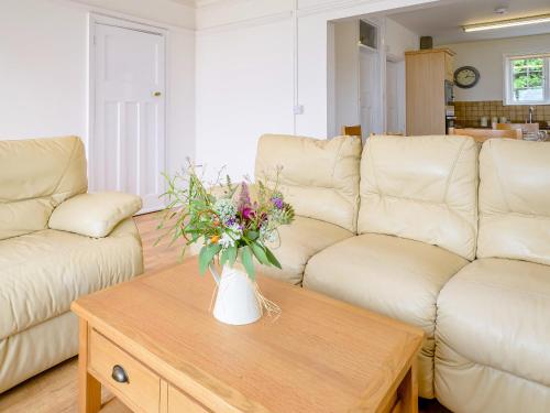 ein Wohnzimmer mit einer Vase aus Blumen auf einem Couchtisch in der Unterkunft On The Beach, East Yardley House - Uk31203 in Downderry