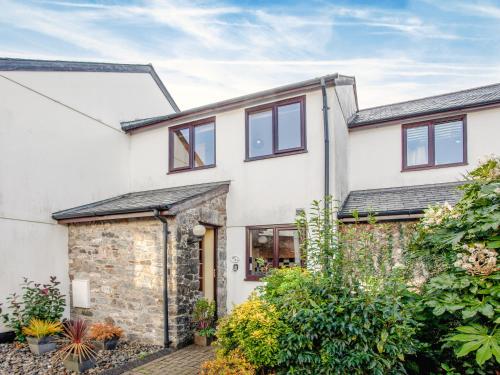 a white house with a stone wall and windows at Ted 'N' Betty's in Buckfastleigh
