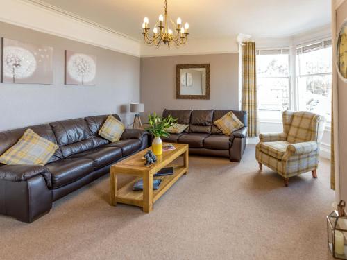 a living room with a leather couch and a table at Littlebay Apartment in Oban