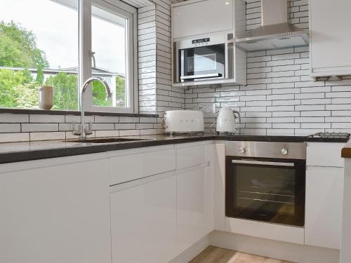 a white kitchen with a sink and a microwave at Bowness Apartment - Uk11016 in Bowness-on-Windermere