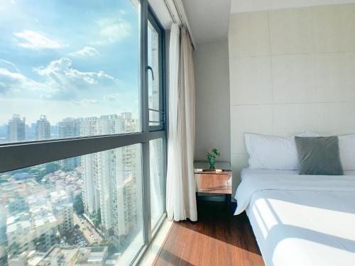 a bedroom with a bed and a large window at Hesheng Hotel Apartment in Shenzhen
