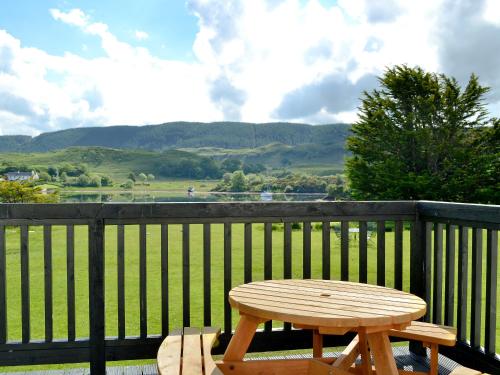 a wooden picnic table sitting on a balcony with a view at Lunga - 28791 in Clachan