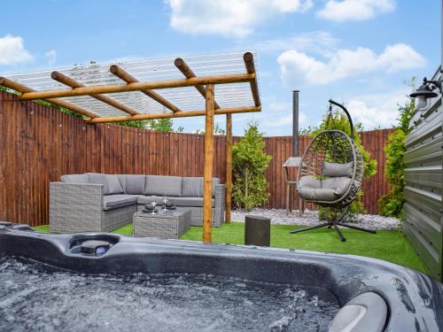 Un patio trasero con jacuzzi y pérgola. en Laurel Pod - Uk47203, en Westhead