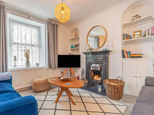 ein Wohnzimmer mit einer blauen Couch und einem Kamin in der Unterkunft Y Ty Glas - Cottage in New Quay