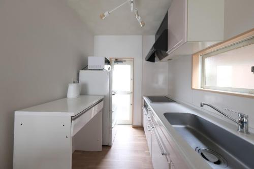 a white kitchen with a sink and a refrigerator at ベル高崎 in Takasaki