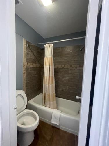 y baño con aseo y bañera con cortina de ducha. en Western Capri Motel, en Tulsa
