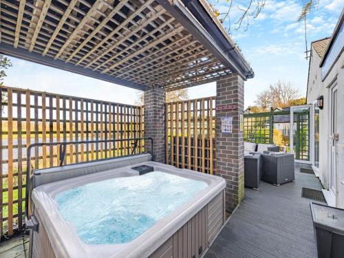 einen Whirlpool auf einer Terrasse mit einer Pergola in der Unterkunft Ty Llyn Cottage in Brynteg
