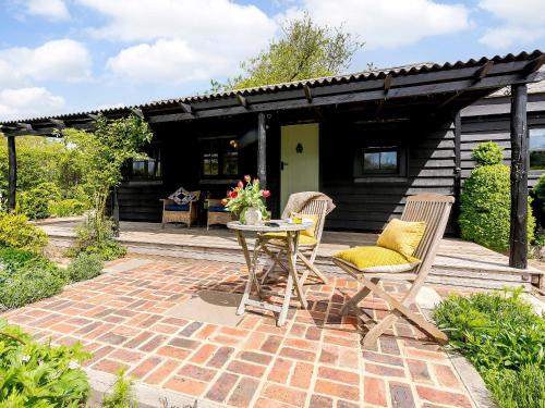 a patio with a table and chairs and a house at Brook Farm Annex in Tenterden