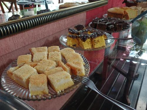 two plates of cakes and other pastries on a counter at Pousada Colonial in Macaé